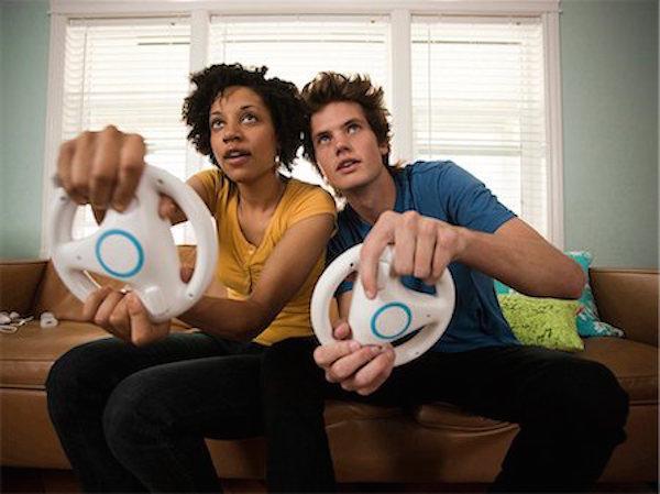 young couple playing video games together on couch